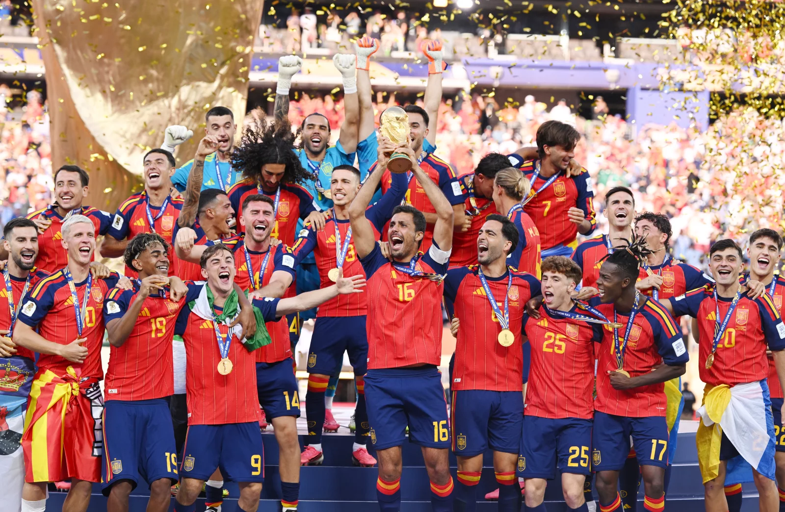 Spain's national football team celebrating their FIFA World Cup victory, lifting the trophy amid gold confetti.